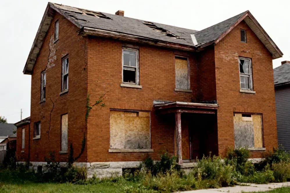 Iowa house with boarded windows and a failing roof, bought as-is with no repairs required.